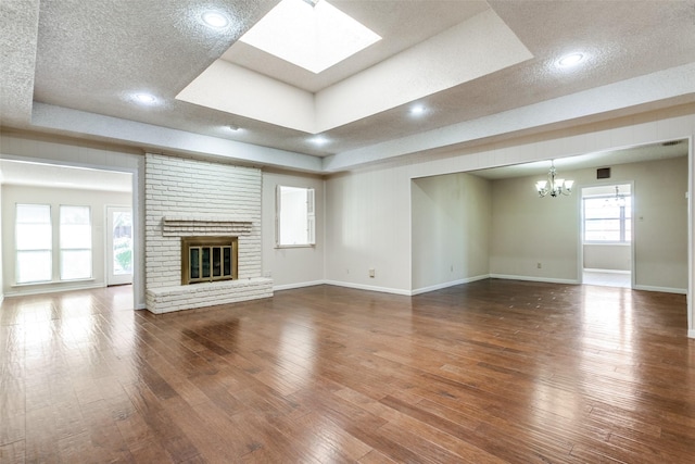 unfurnished living room featuring a tray ceiling, hardwood / wood-style flooring, a textured ceiling, and a fireplace