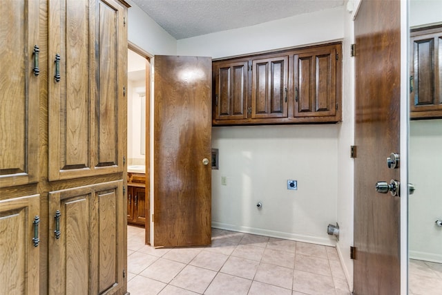 laundry area with light tile patterned flooring, cabinets, hookup for an electric dryer, and a textured ceiling