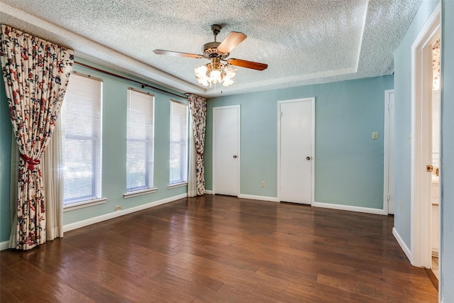 unfurnished bedroom with a textured ceiling, dark hardwood / wood-style floors, ceiling fan, and multiple closets