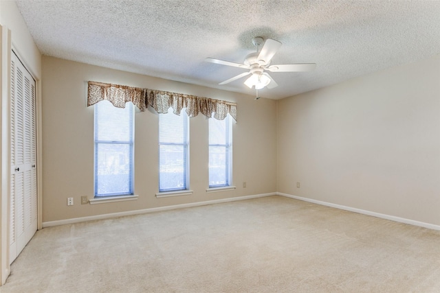 spare room featuring a textured ceiling, light colored carpet, and ceiling fan