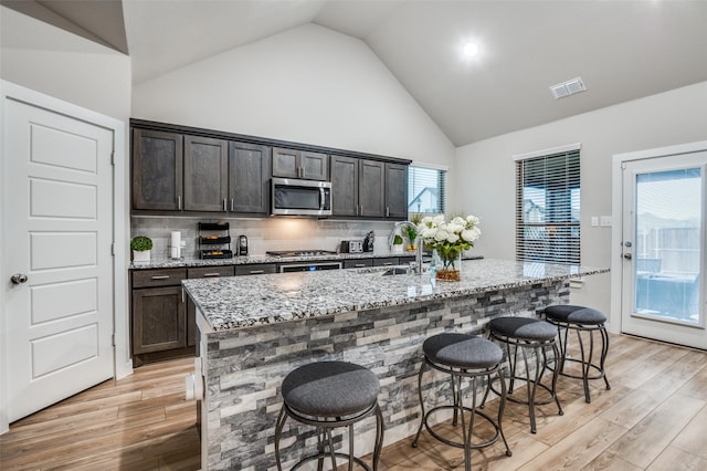 kitchen with appliances with stainless steel finishes, a kitchen bar, and an island with sink