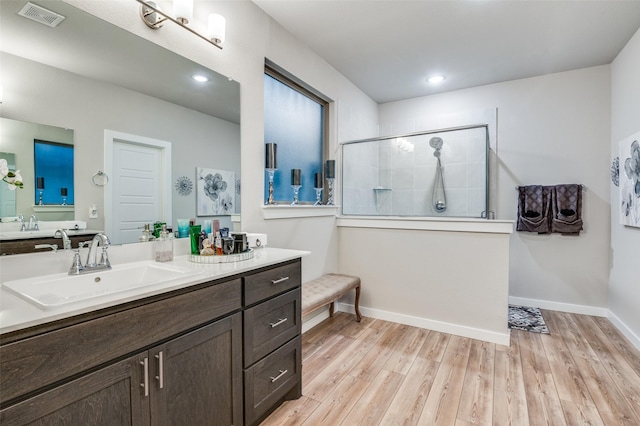 bathroom with wood-type flooring, tiled shower, and vanity