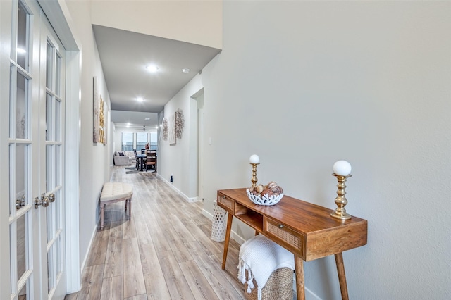 corridor with light hardwood / wood-style floors and french doors