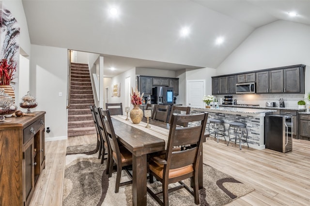 dining area with high vaulted ceiling and light hardwood / wood-style floors