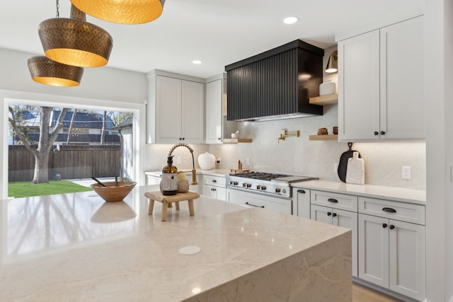 kitchen featuring sink, hanging light fixtures, extractor fan, light stone countertops, and stainless steel gas stovetop