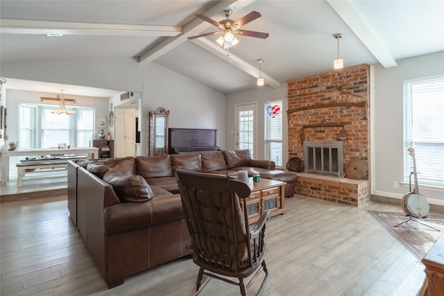 living room featuring lofted ceiling with beams, ceiling fan, a brick fireplace, and light hardwood / wood-style floors