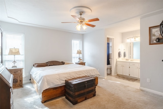 bedroom featuring ceiling fan, sink, light carpet, and ensuite bath