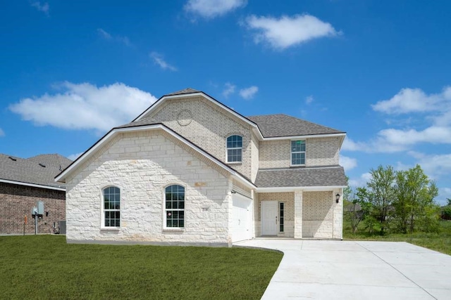 french country style house with roof with shingles, concrete driveway, an attached garage, brick siding, and a front yard