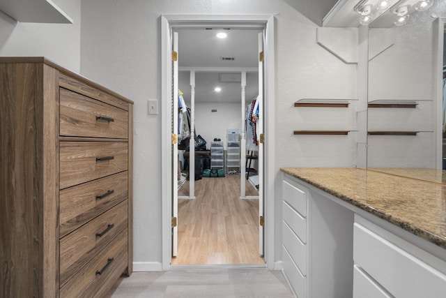 walk in closet with light hardwood / wood-style flooring