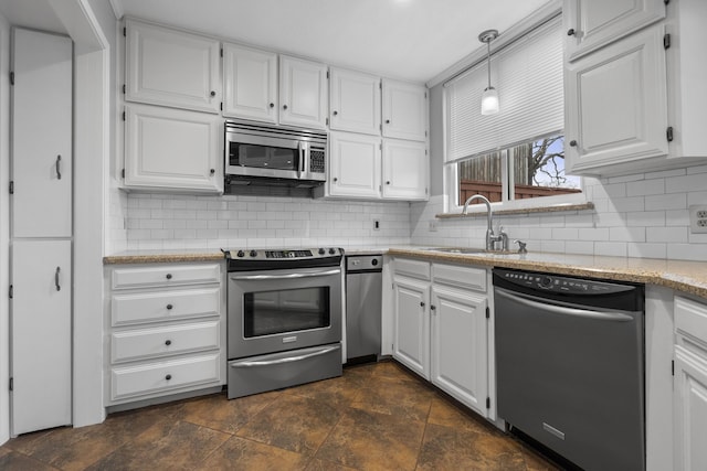 kitchen featuring decorative light fixtures, sink, white cabinets, decorative backsplash, and stainless steel appliances