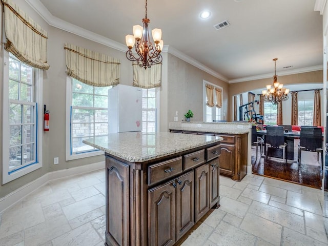 kitchen with hanging light fixtures, a kitchen island, dark brown cabinetry, and a chandelier