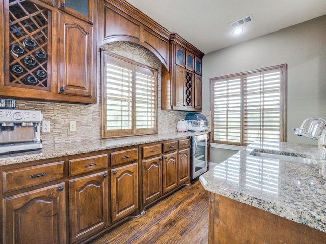 kitchen featuring dark hardwood / wood-style floors, sink, backsplash, beverage cooler, and light stone counters