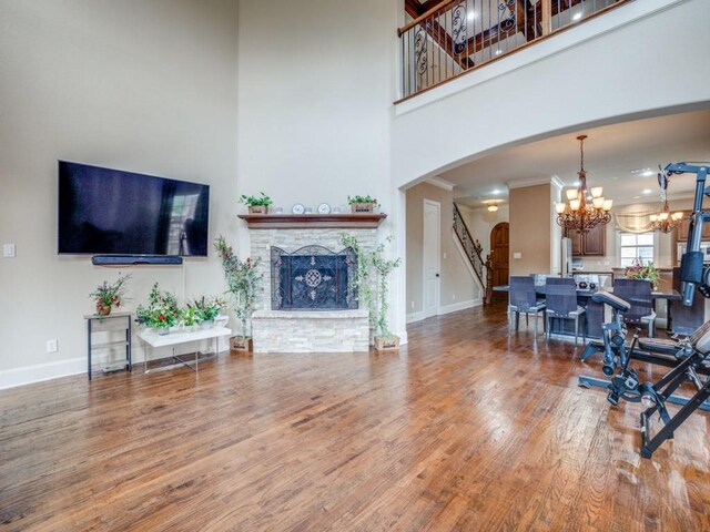 living room featuring hardwood / wood-style flooring, ornamental molding, a chandelier, and a high ceiling