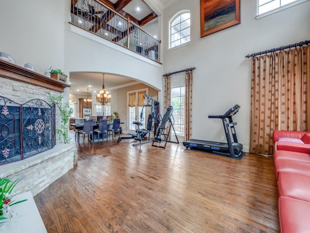 living room with hardwood / wood-style flooring, a towering ceiling, crown molding, and an inviting chandelier