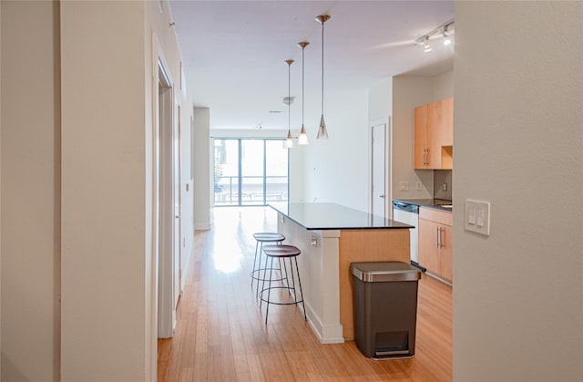 kitchen featuring pendant lighting, dishwasher, a center island, light brown cabinets, and light wood-type flooring