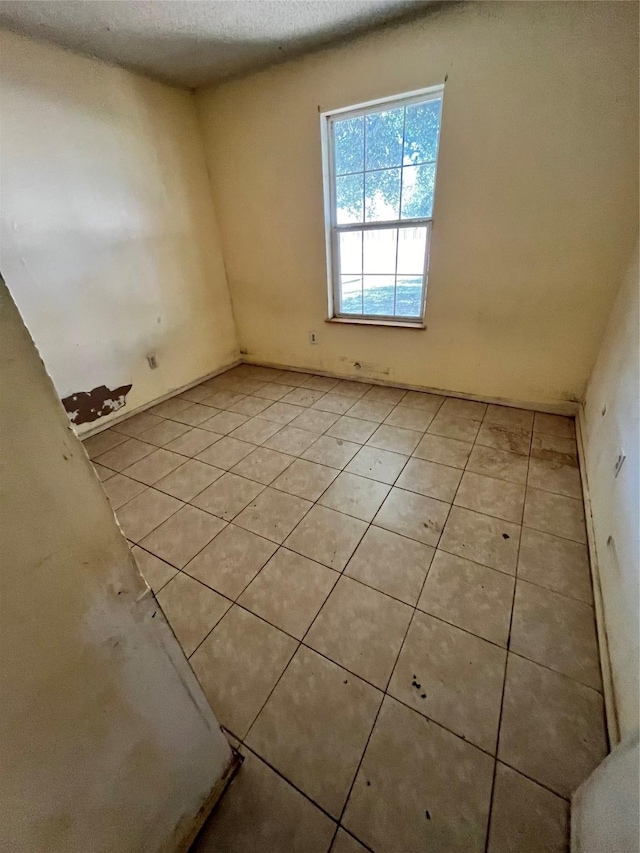 tiled empty room featuring a textured ceiling