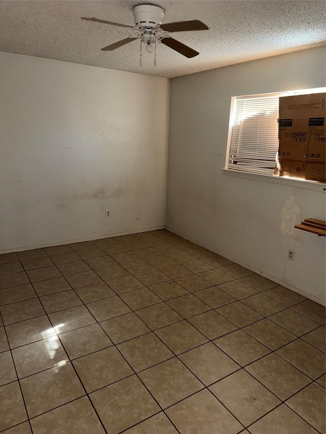 unfurnished room featuring ceiling fan, light tile patterned floors, and a textured ceiling