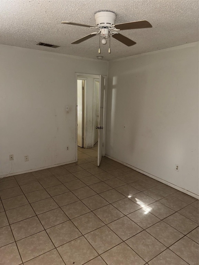 tiled spare room with ceiling fan and a textured ceiling