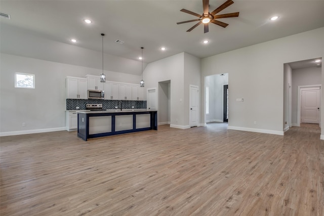 kitchen with appliances with stainless steel finishes, pendant lighting, white cabinetry, a kitchen island with sink, and ceiling fan