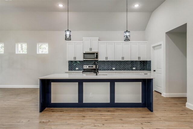 kitchen with stainless steel appliances, sink, an island with sink, and hanging light fixtures