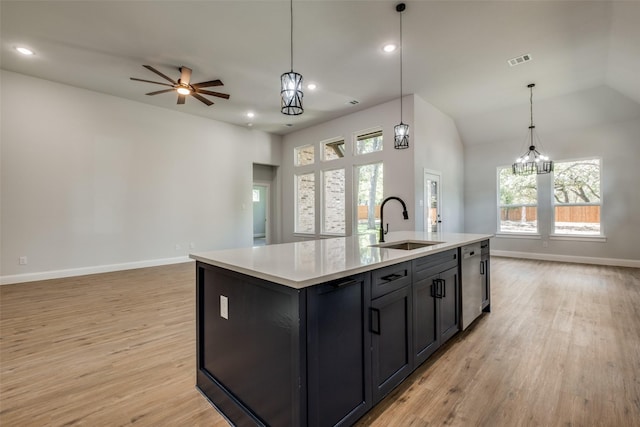 kitchen featuring sink, hanging light fixtures, a kitchen island with sink, ceiling fan, and light hardwood / wood-style flooring