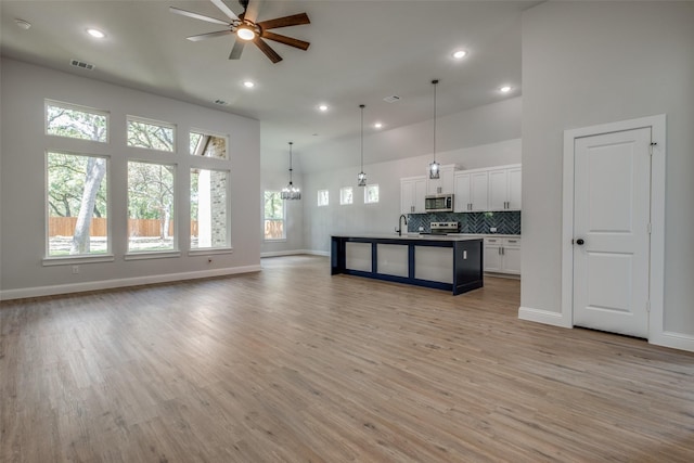 living room featuring sink, ceiling fan with notable chandelier, high vaulted ceiling, and light hardwood / wood-style flooring