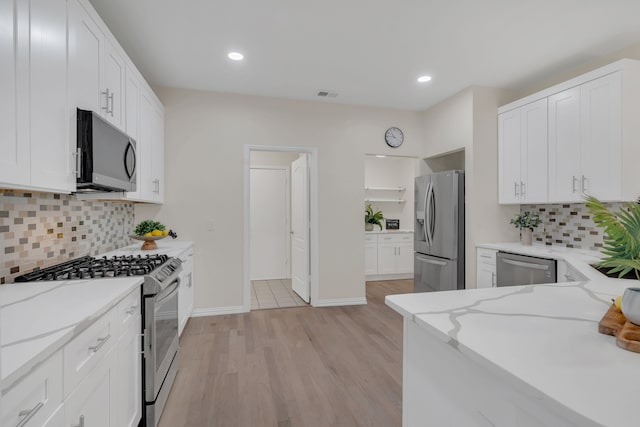 kitchen featuring stainless steel appliances, light stone countertops, light hardwood / wood-style flooring, and white cabinets