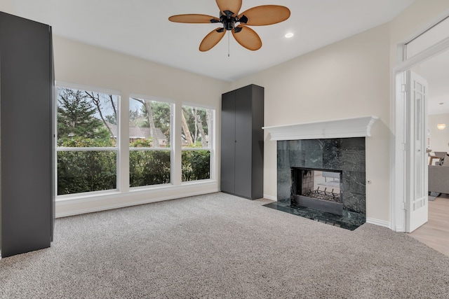 unfurnished living room featuring ceiling fan, a fireplace, and light carpet