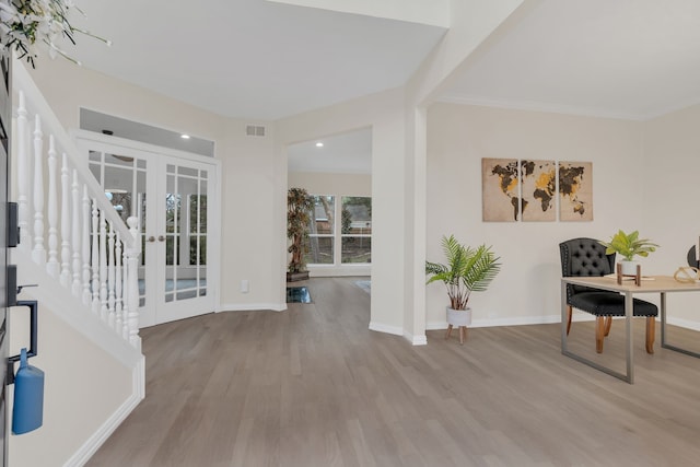 entryway featuring french doors, crown molding, and light hardwood / wood-style floors