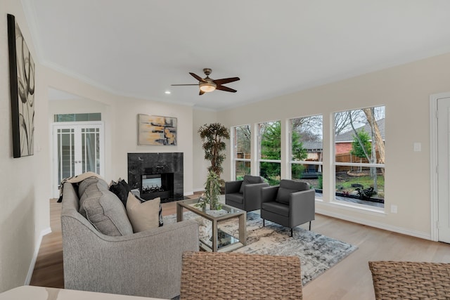 living room featuring french doors, crown molding, hardwood / wood-style flooring, ceiling fan, and a premium fireplace