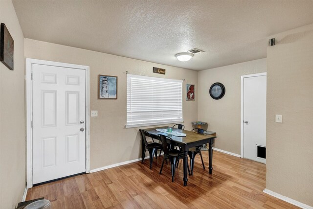 dining space featuring a textured ceiling and light wood-type flooring