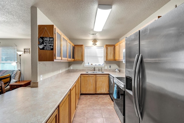 kitchen with light tile patterned flooring, appliances with stainless steel finishes, sink, and a textured ceiling