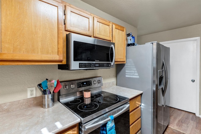 kitchen with light brown cabinetry and appliances with stainless steel finishes