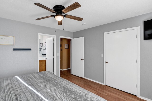 unfurnished bedroom featuring ceiling fan, ensuite bath, and light hardwood / wood-style flooring