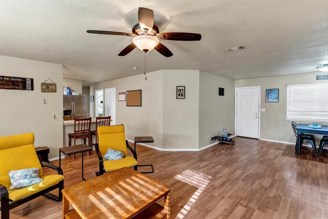 sitting room with wood-type flooring, ceiling fan, and a textured ceiling