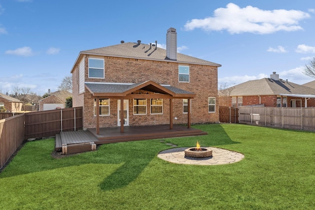 rear view of property featuring a wooden deck, an outdoor fire pit, and a yard