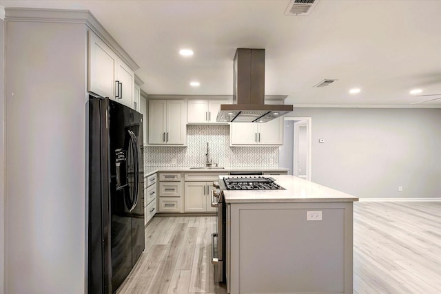 kitchen featuring black fridge with ice dispenser, tasteful backsplash, light hardwood / wood-style flooring, a kitchen island, and island exhaust hood