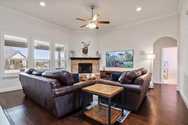 living room featuring dark hardwood / wood-style flooring, a brick fireplace, and crown molding