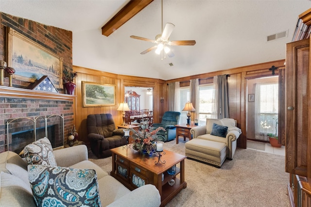 carpeted living room featuring lofted ceiling with beams, a brick fireplace, ceiling fan, and wood walls