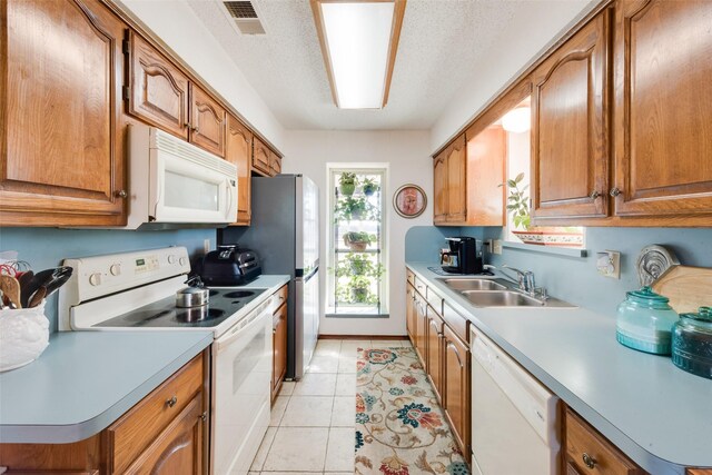 kitchen with sink, white appliances, a textured ceiling, and light tile patterned flooring