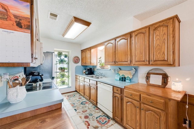 kitchen with sink, light tile patterned floors, a textured ceiling, and dishwasher