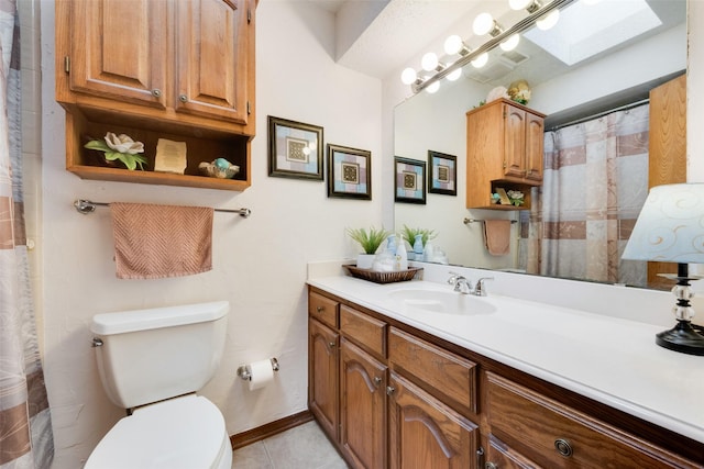 bathroom featuring tile patterned flooring, toilet, vanity, and a skylight