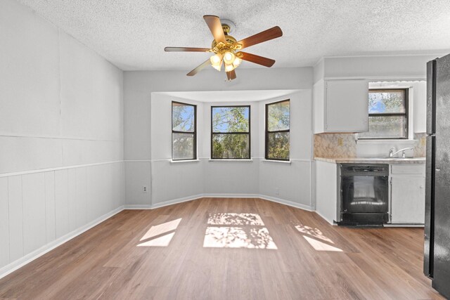 kitchen featuring black appliances, white cabinets, ceiling fan, light hardwood / wood-style floors, and a textured ceiling