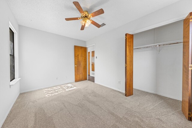 unfurnished bedroom featuring ceiling fan, a closet, light carpet, and a textured ceiling