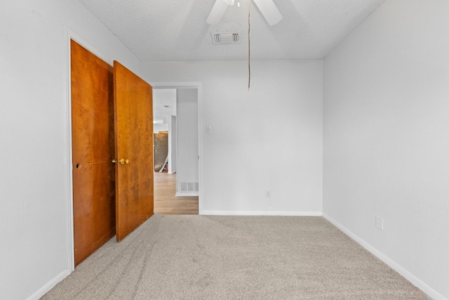 empty room with ceiling fan, carpet, and a textured ceiling