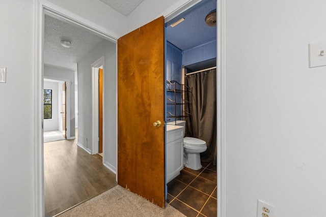 bathroom featuring tile patterned flooring, vanity, toilet, and a textured ceiling