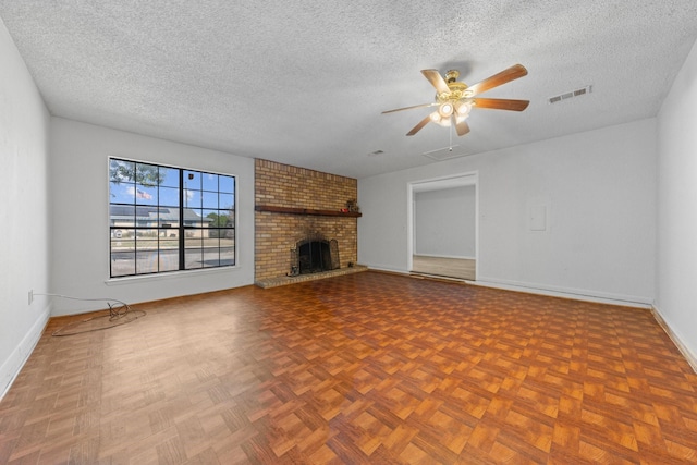 unfurnished living room featuring ceiling fan, parquet flooring, a brick fireplace, and a textured ceiling