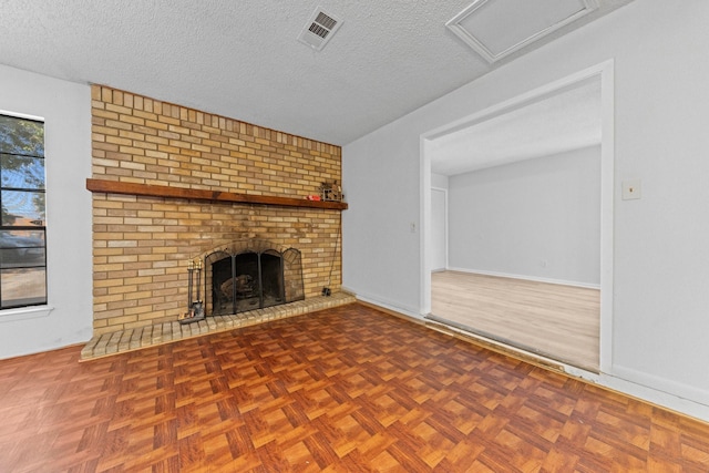 unfurnished living room featuring a brick fireplace, parquet floors, and a textured ceiling