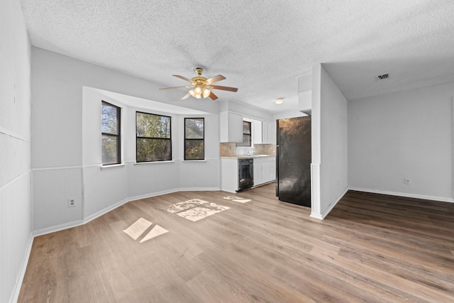 unfurnished living room featuring a textured ceiling, ceiling fan, and light hardwood / wood-style flooring