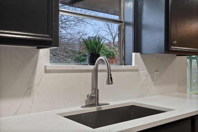 room details featuring light stone countertops, sink, and decorative backsplash